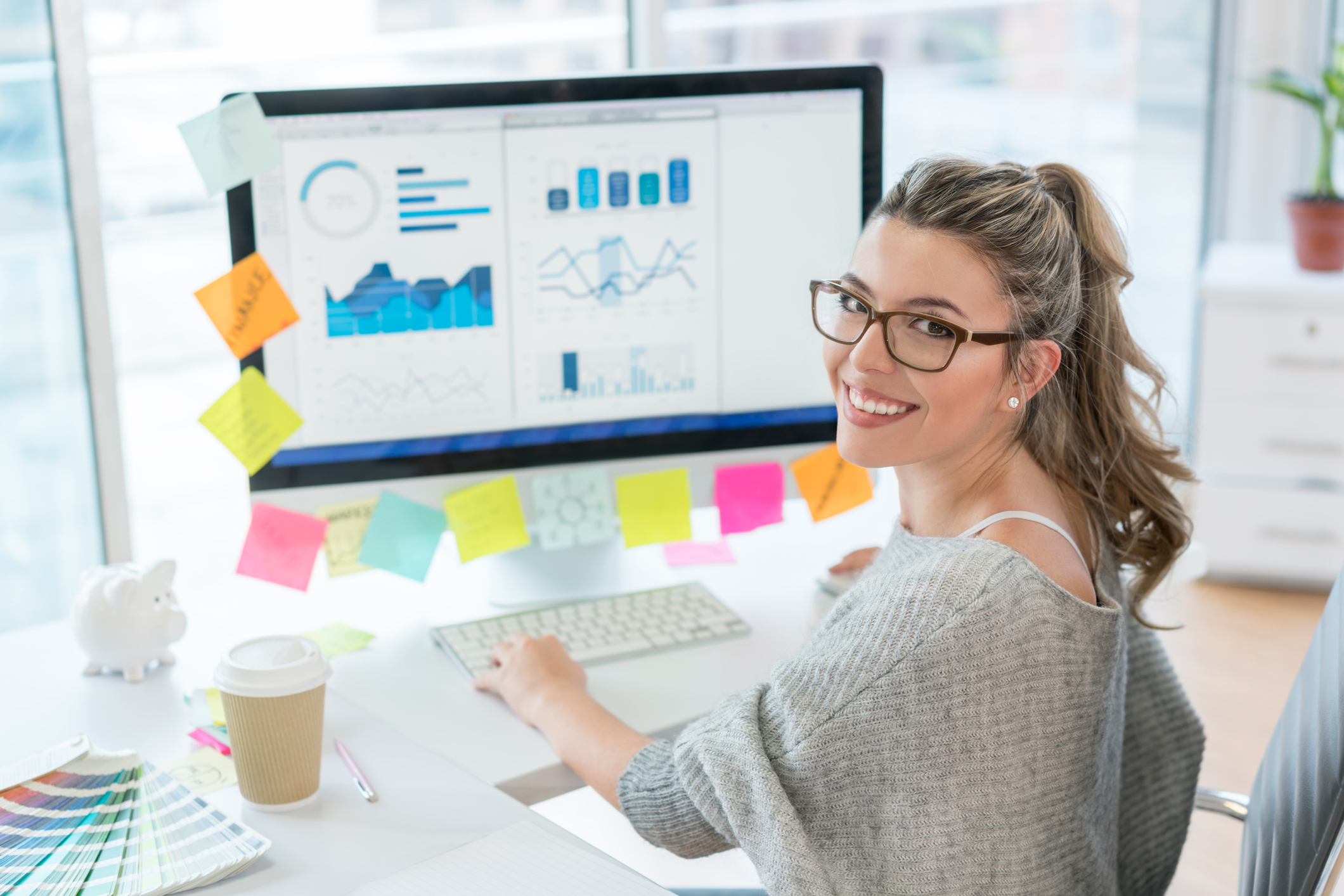 Woman working at the office on her computer and looking at the camera smiling