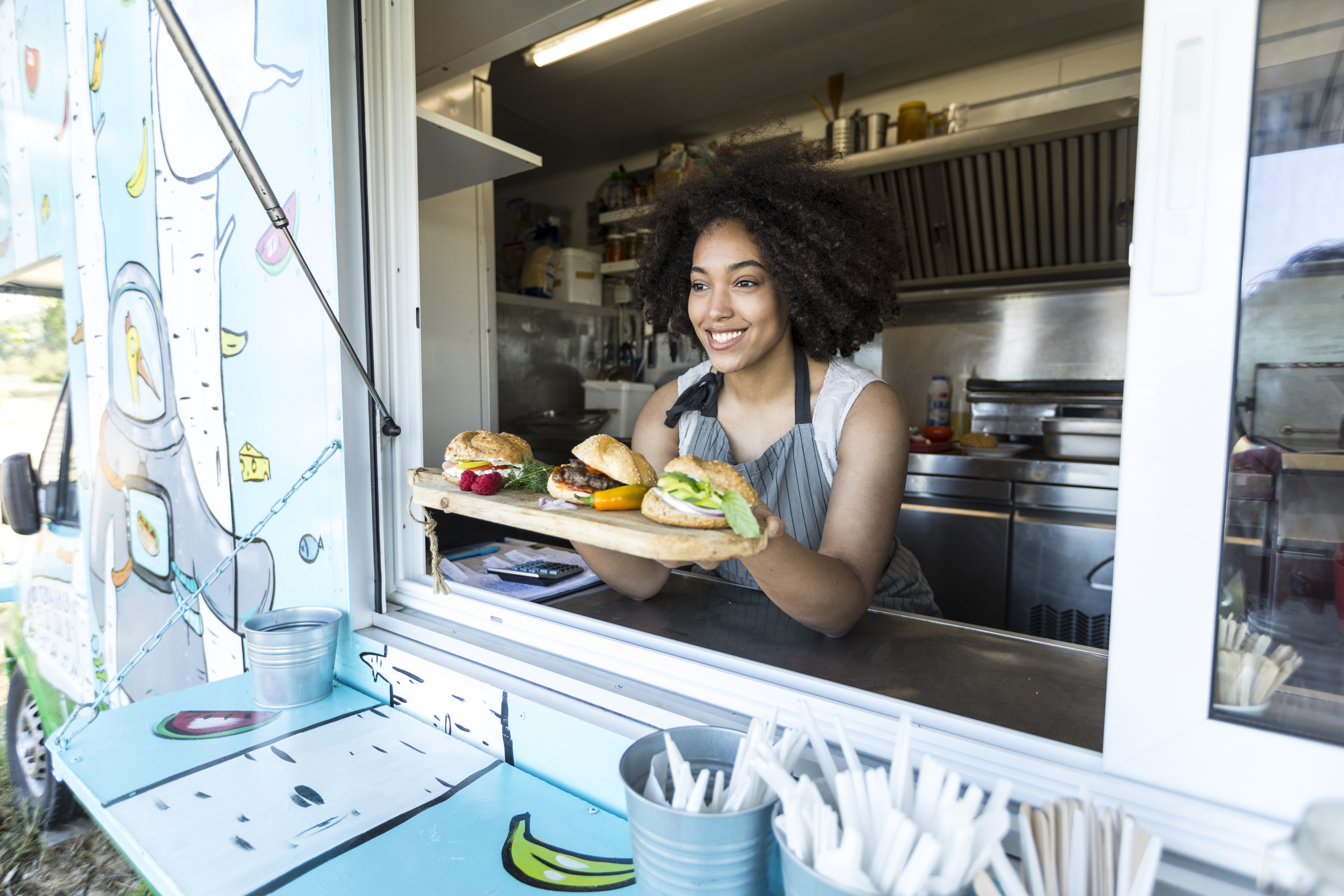 Woman behind counter displaying burgers